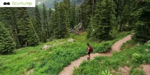 A woman climbing a mountain with a bag on her back causing piriformis pain