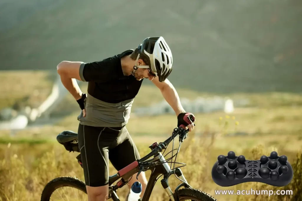 A man holding his bike with one hand and his lower back with the other, pain from excessive riding uphill, Acu-hump massage tool for relief