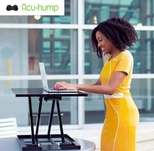 A black woman is standing and working with a laptop