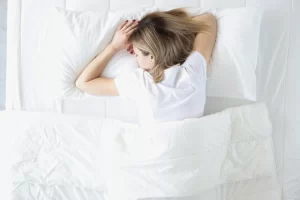 Woman suffering from piriformis pain sleeping on her stomach in bed to avoid compressing buttock muscles