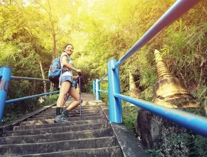 A hiking female climbs a mountain and looks back while standing on a long staircase