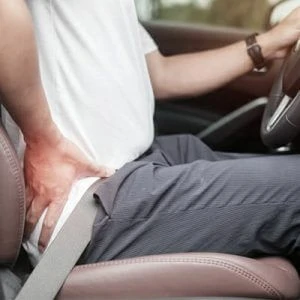 Feeling pain in the lower back while driving, the driver puts his hands on his lower back