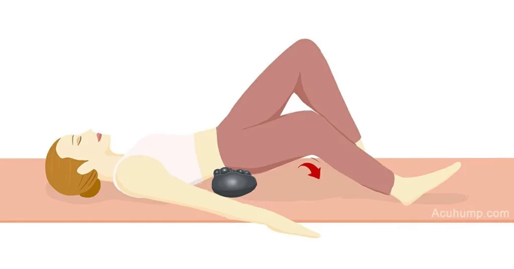 A woman lies on a yoga mat, puts the Acu-hump under the SI Joint, swings one leg, relieves sciatica lower back pain