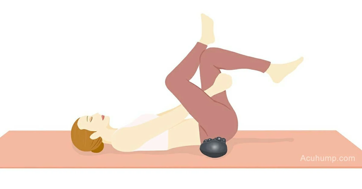 A woman, on a yoga mat, utilizes a piriformis massage tool for supine stretching to relieve pain